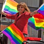 Jane Velez-Mitchell waving pride flags from a car