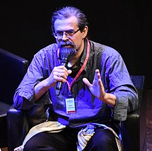 Adrian Tchaikovsky speaking into a microphone
